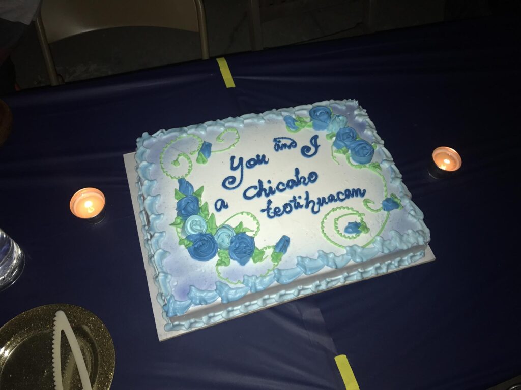 A cake decorated with blue flowers and icing that reads