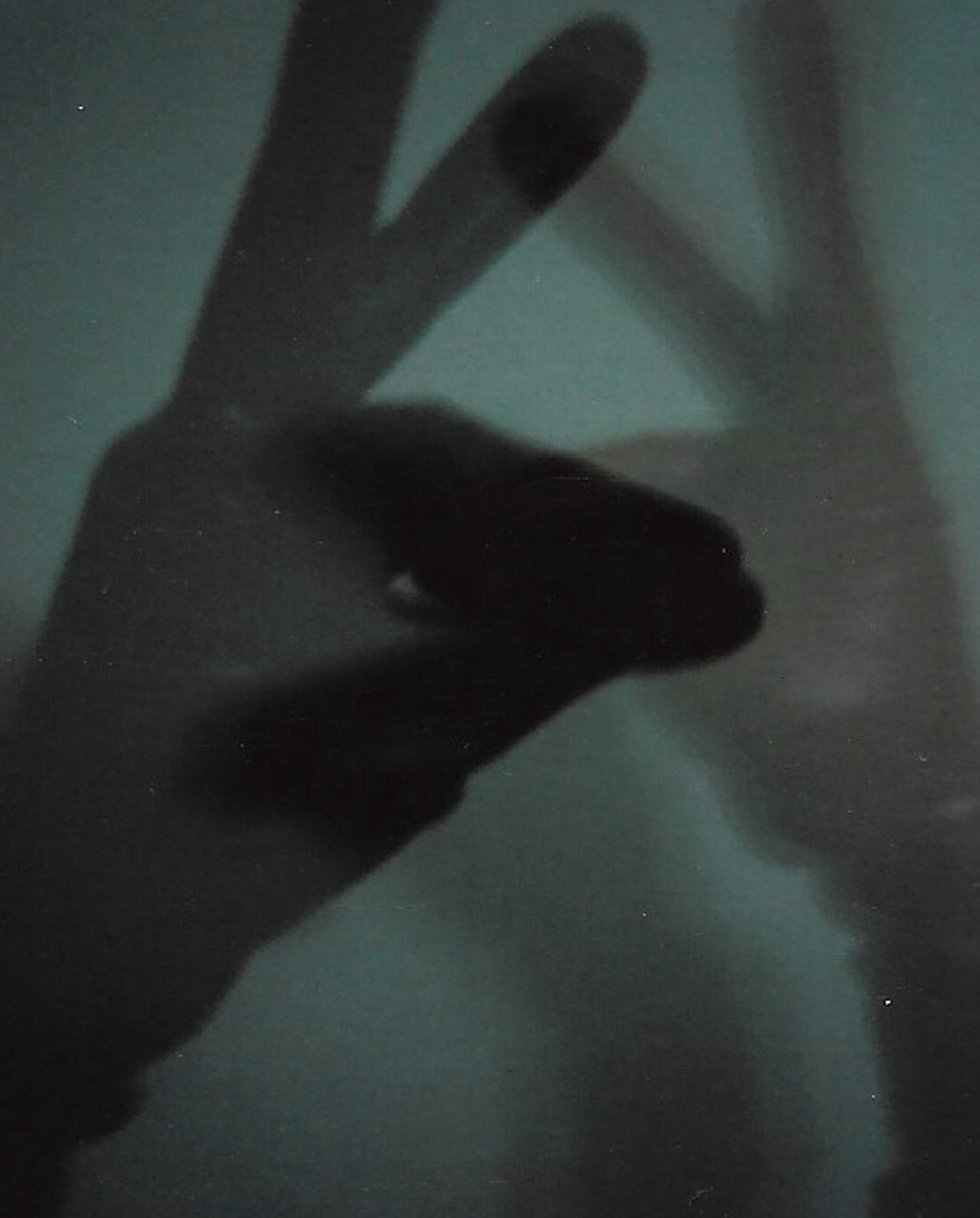 Overlapping shadows of hands that form an enigmatic figure over a blue background.